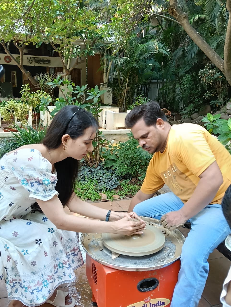 People hand building pottery at a shared table