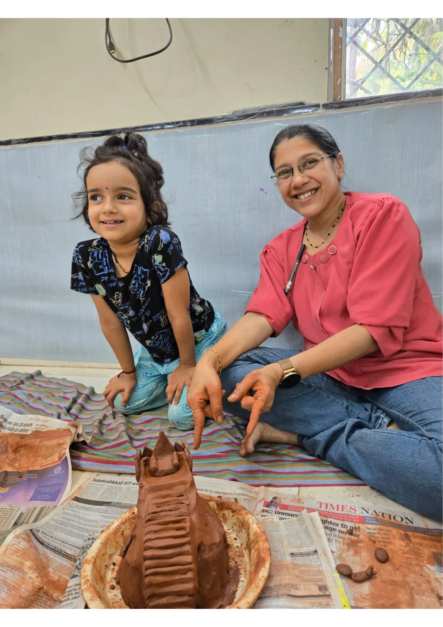 Six people holding up their clay creations at a table.