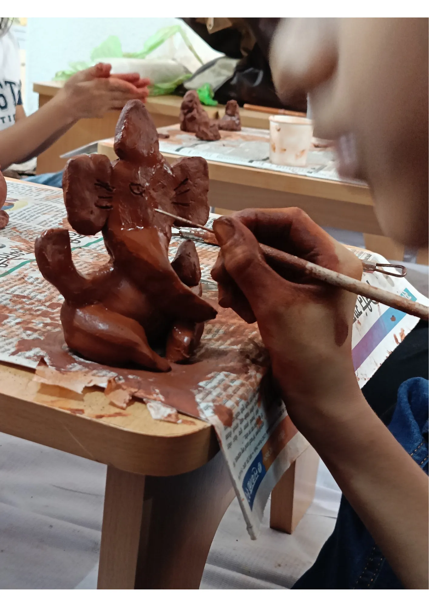 Close up of someone painting a small clay Ganesha statue.